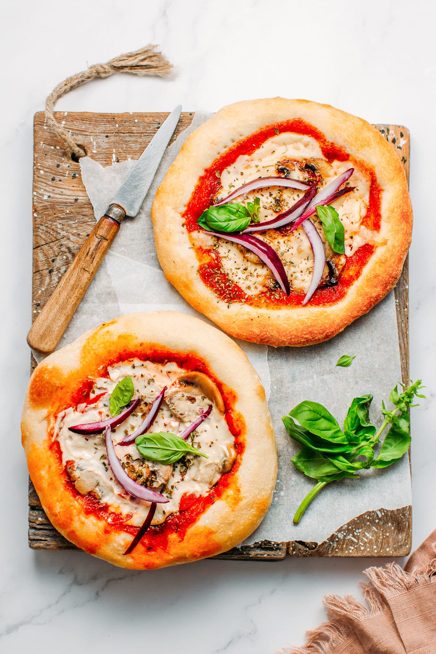 Two mini vegan pizza on a wooden board.