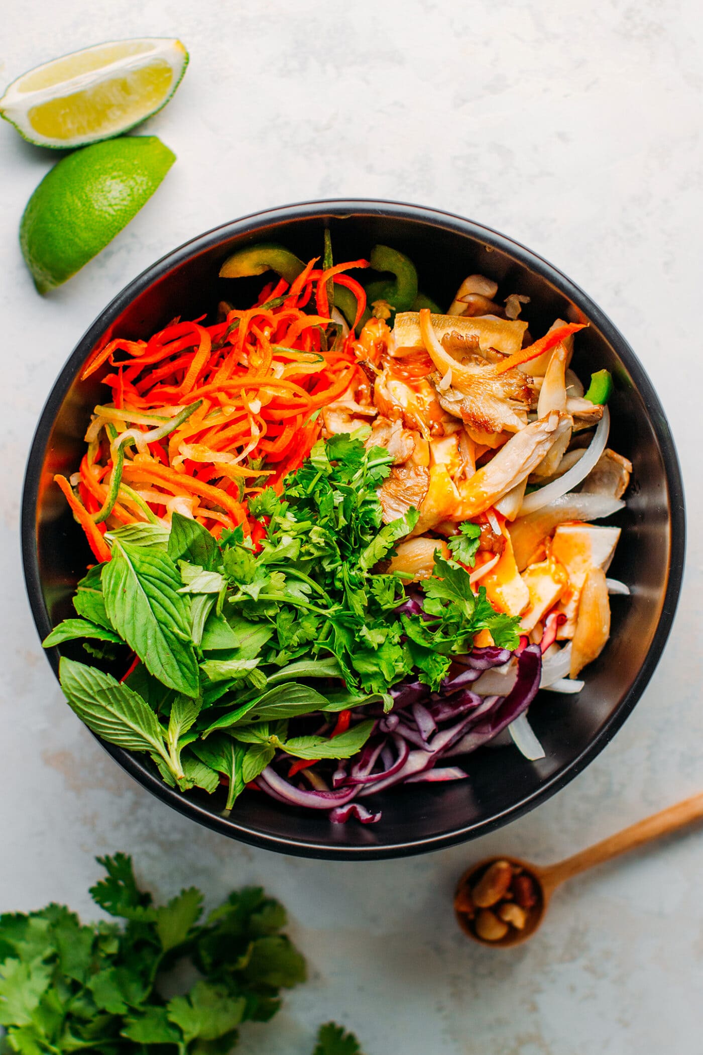 Carrots, oyster mushrooms, tofu, cabbage, basil, and cilantro in a bowl.