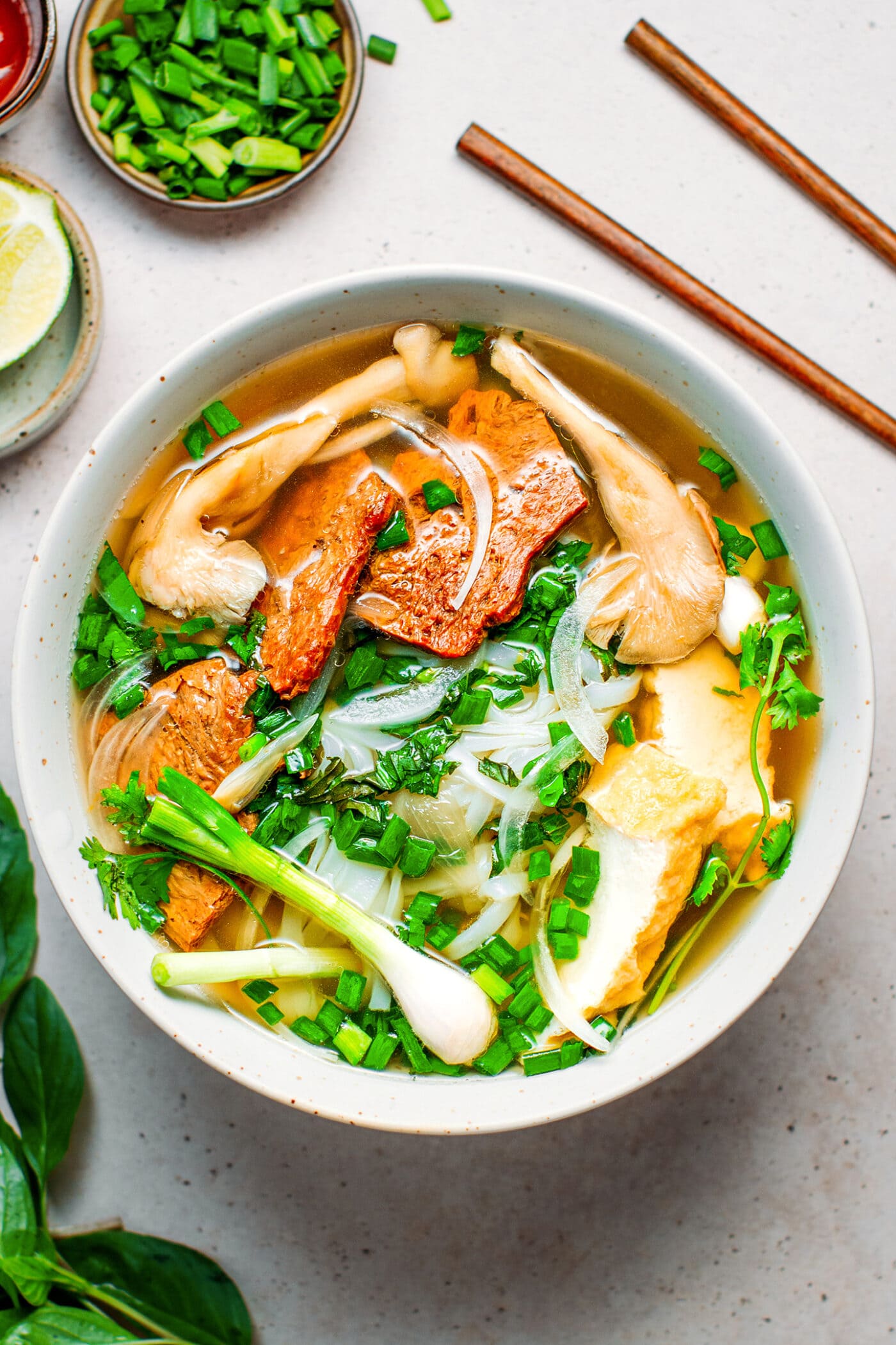 Bowl of vegan Pho with beef, tofu, mushrooms, scallions, and cilantro.