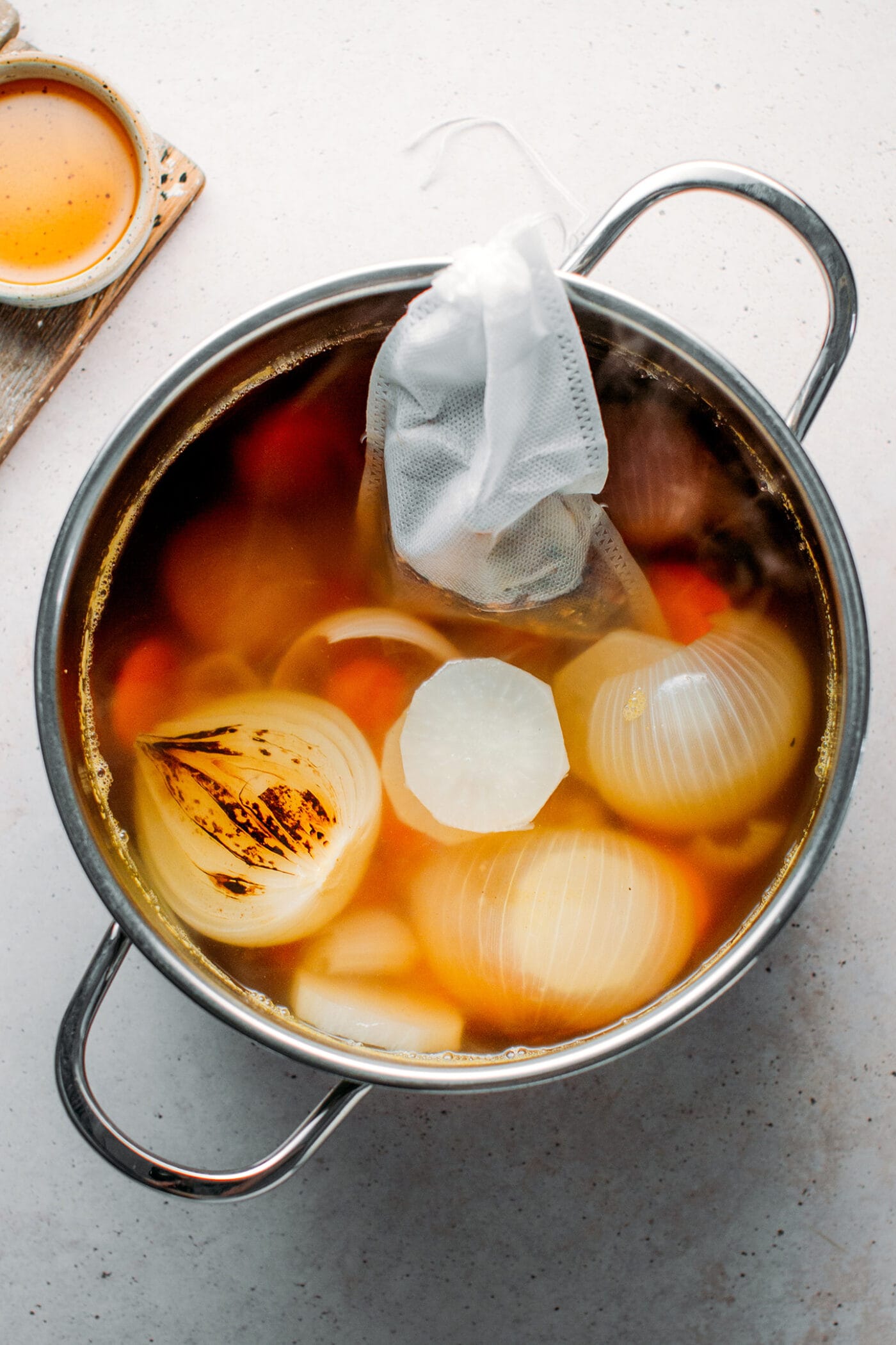 Pho broth with spices bag in a pot.