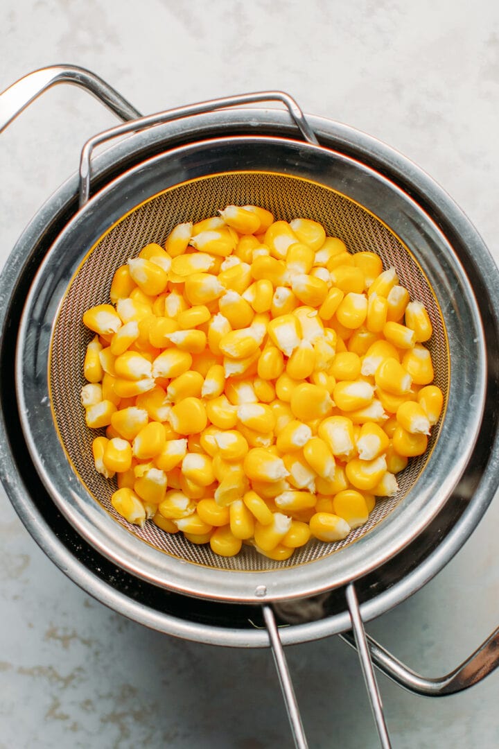 Drained corn in a sieve.