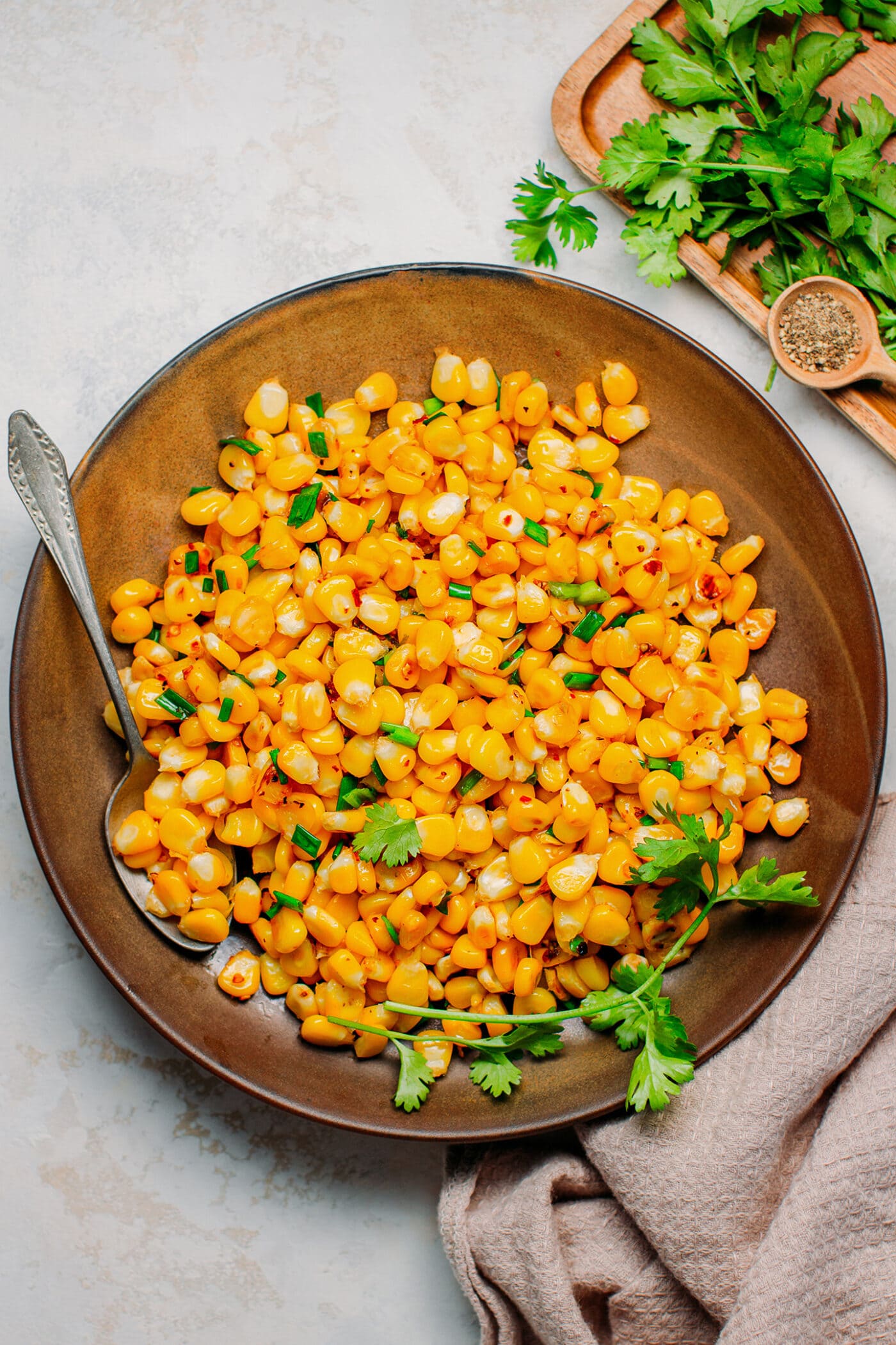 Buttered corn with scallions on a plate.