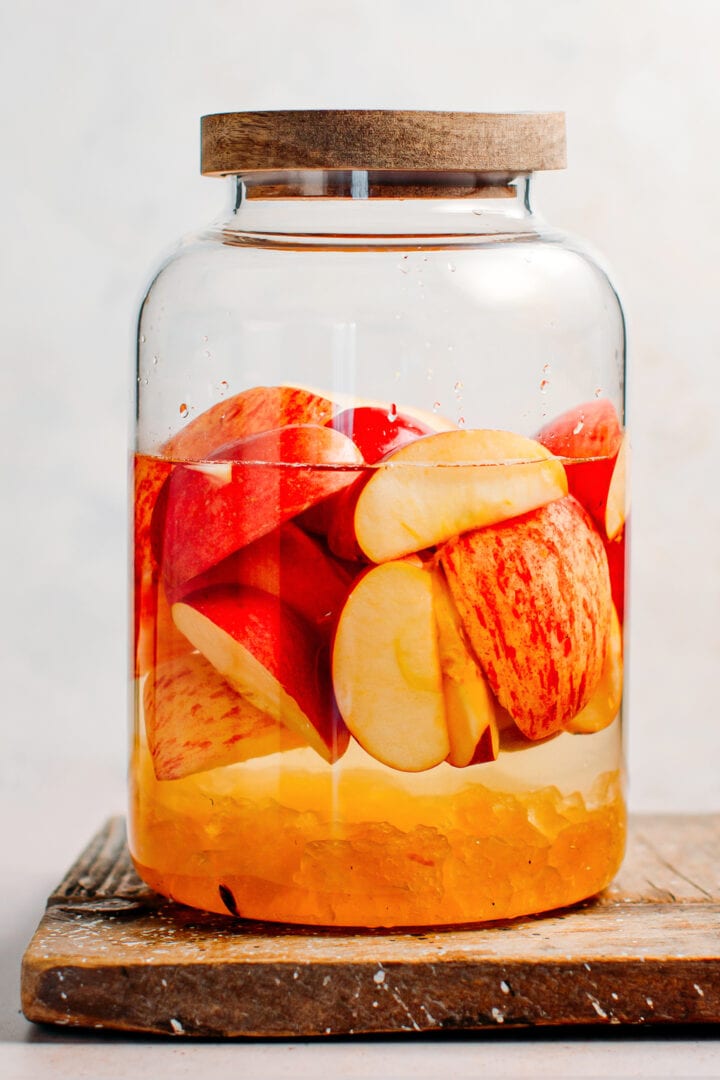 Apples, sugar, and vodka in a glass jar.