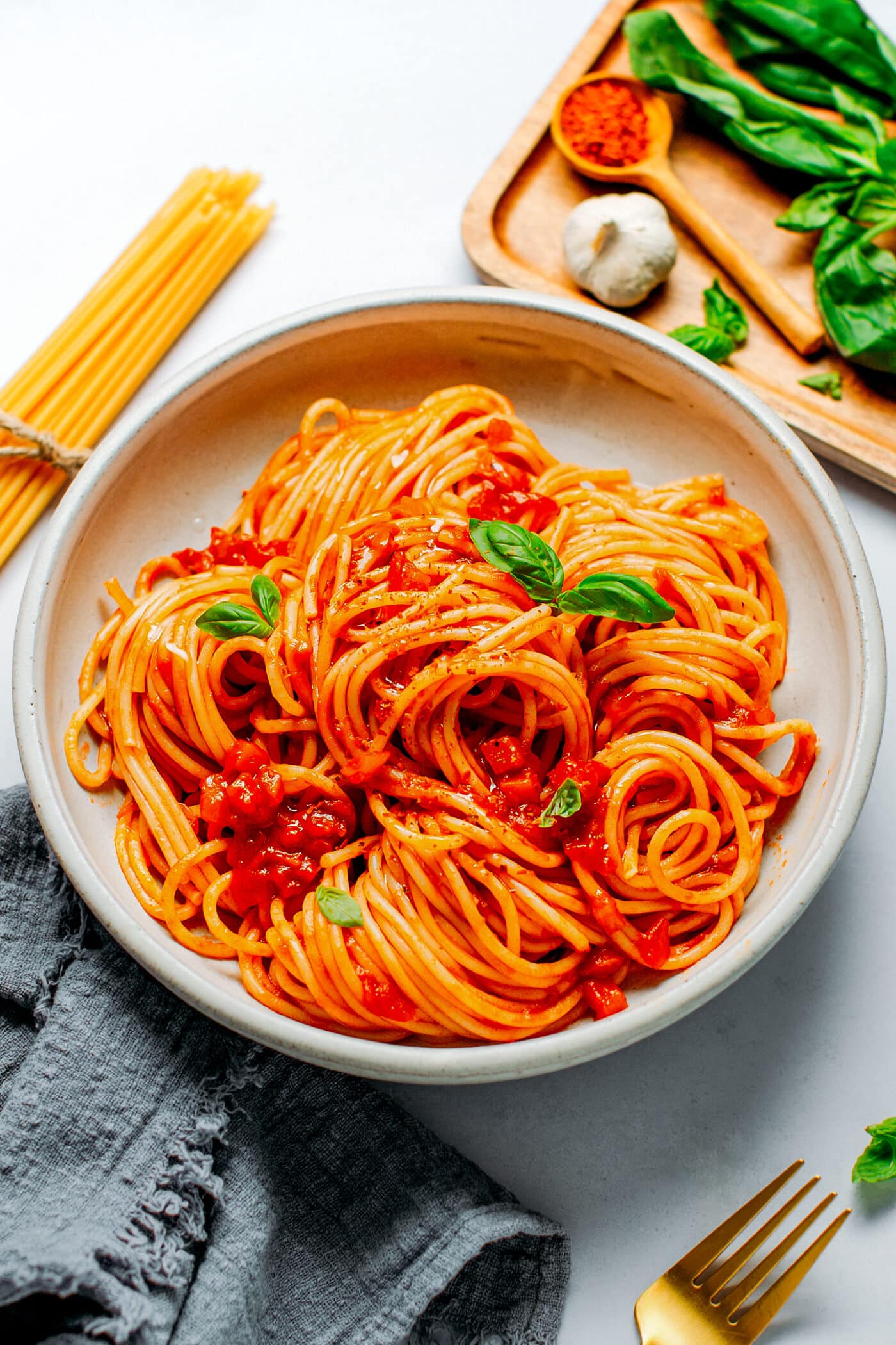 Spaghetti arrabbiata on a plate, topped with fresh basil and chili.