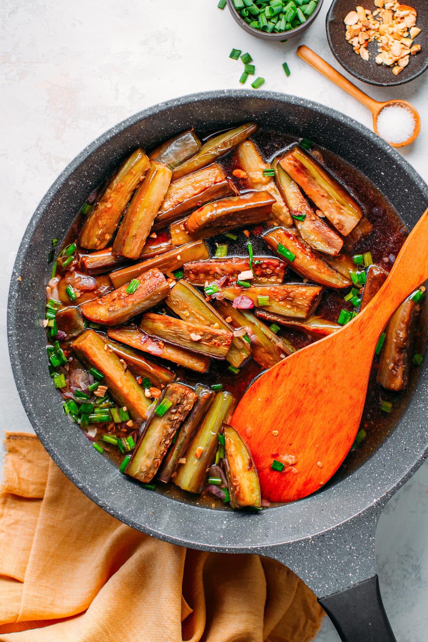 Sautéed eggplants in a skillet with green onions and shallots.