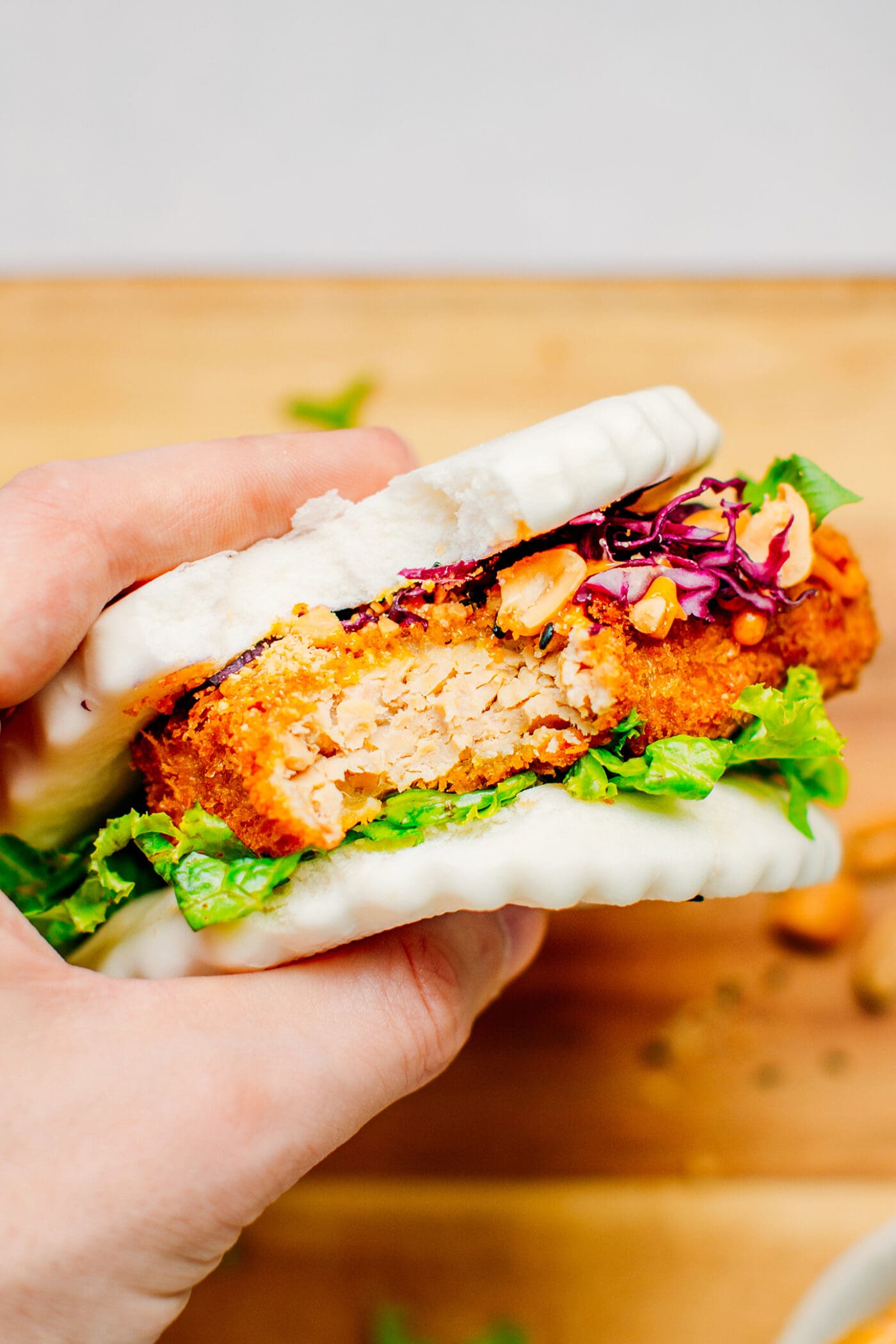 Bao bun with panko tempeh, lettuce, peanuts, and red cabbage.