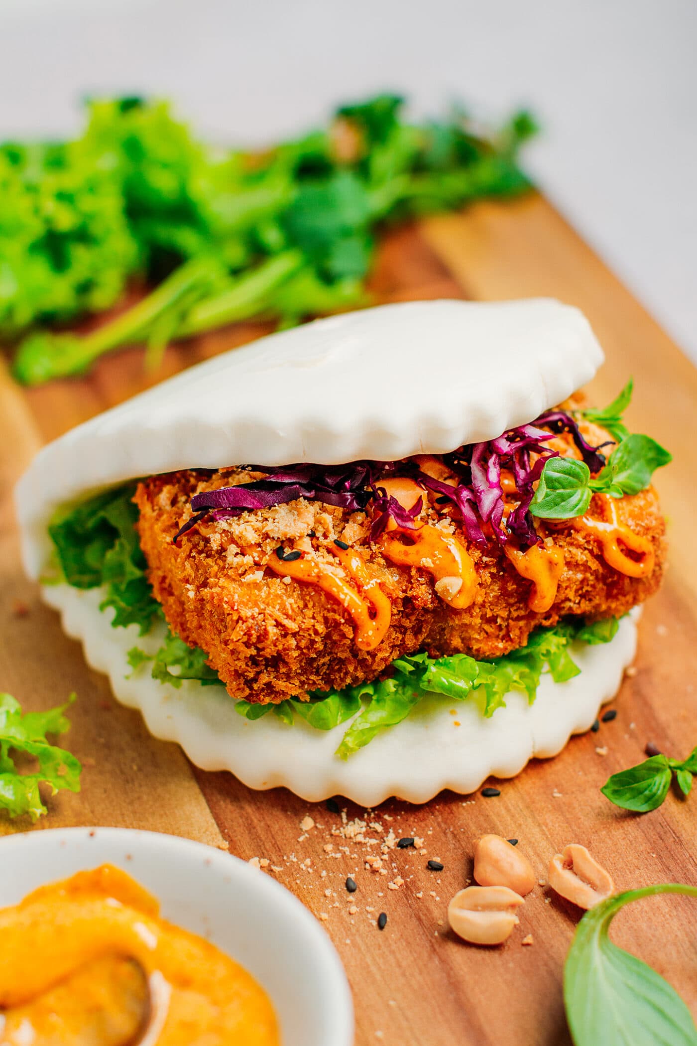 Gua bao with katsu tempeh, curried mayo sauce, lettuce, red cabbage, and peanuts.