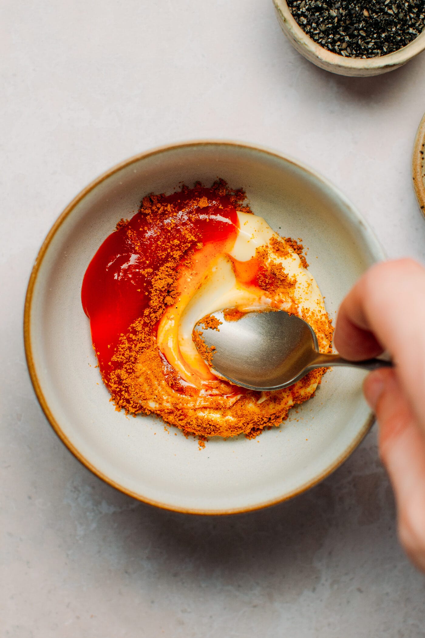 Mixing mayo with chili sauce and curry powder.