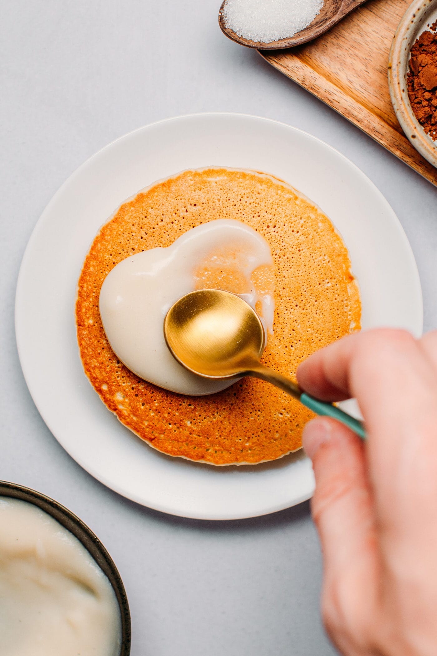 Spreading vanilla cream on top of pancakes.