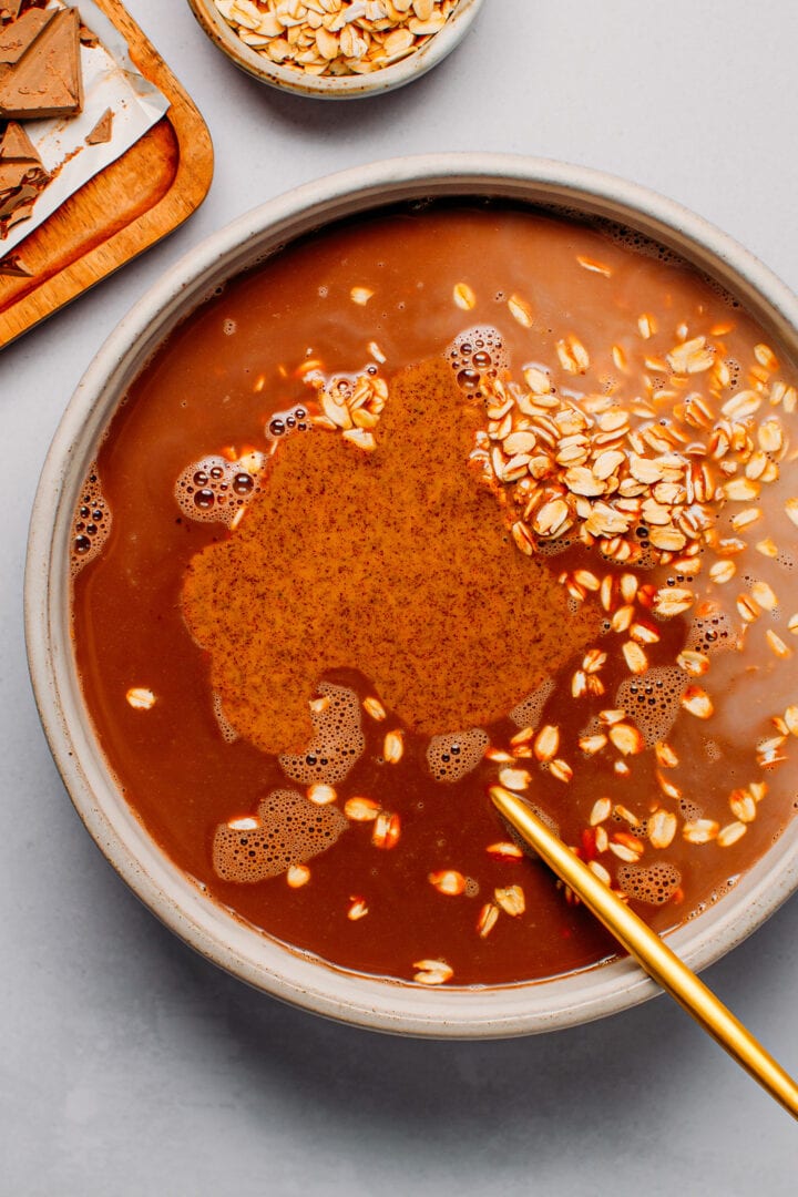 Stirring oats with hazelnut butter and cacao in a bowl.