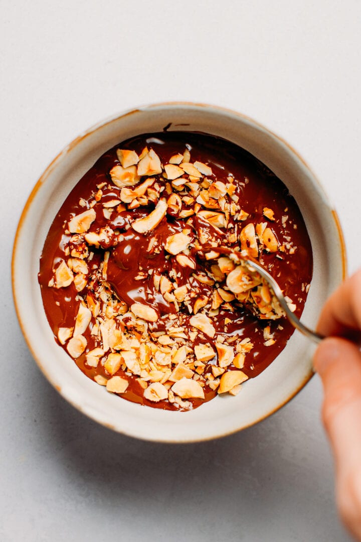 Stirring melted chocolate with chopped hazelnuts.