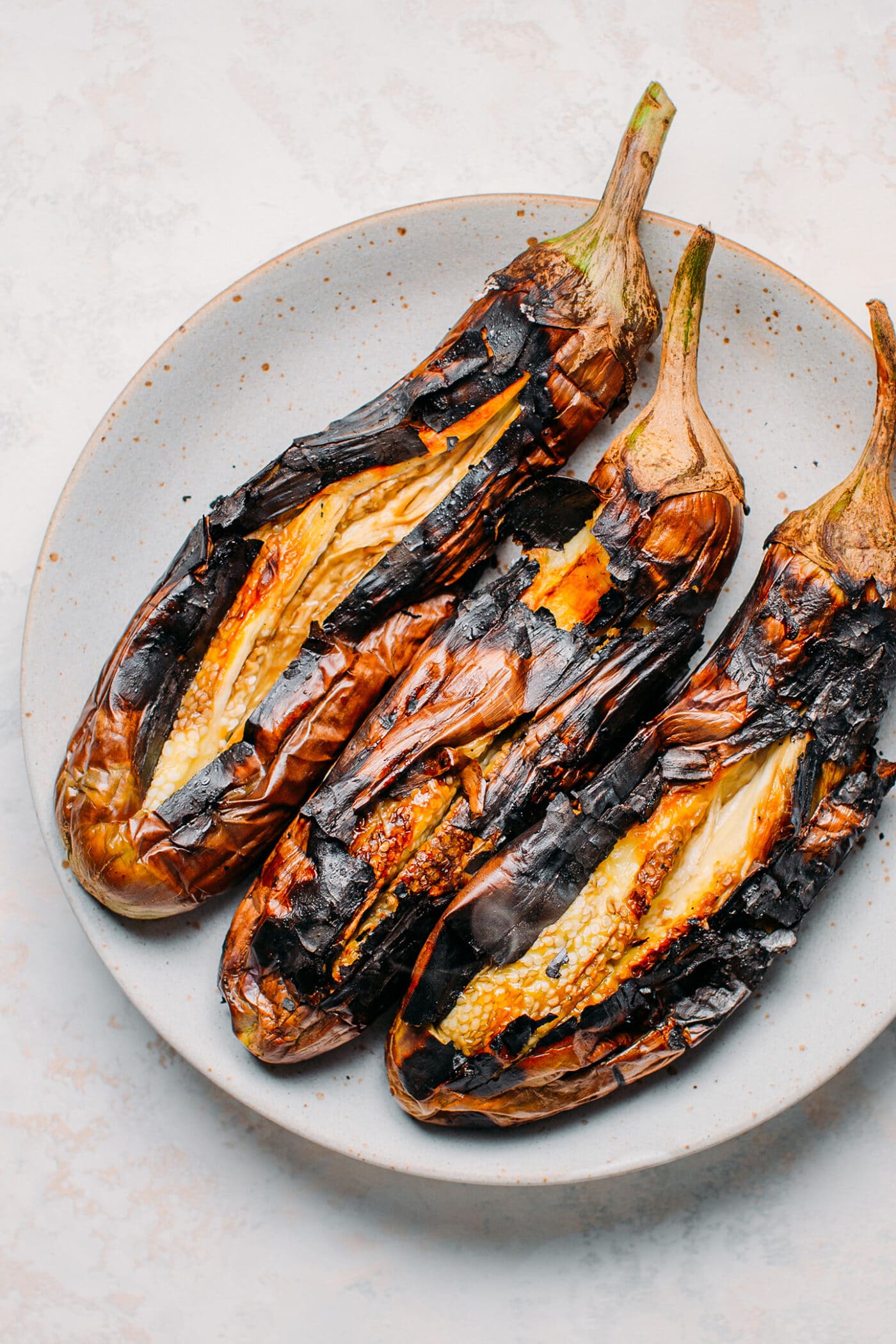 Charred eggplants on a plate.