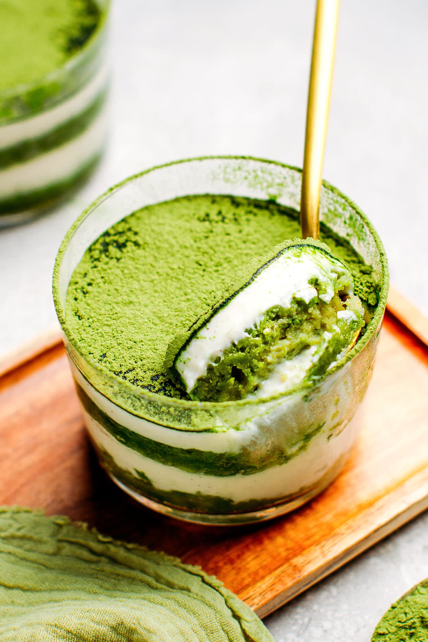 Spoon digging into a ramekin of matcha tiramisu.