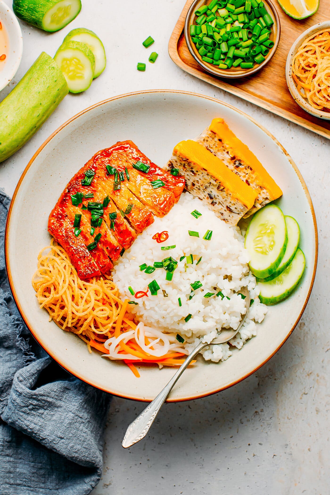 Plate of broken rice with tofu meatloaf, vegan ribs, cucumber, and pickles.