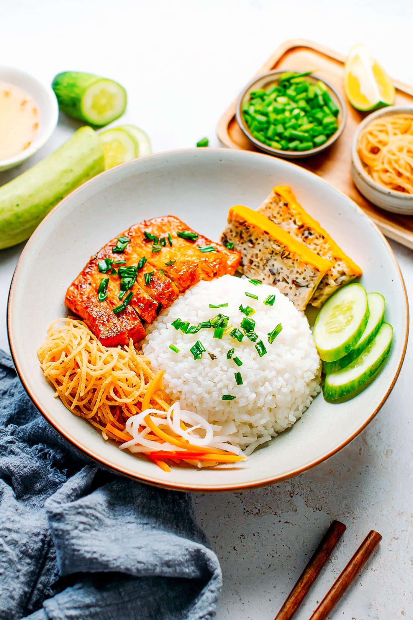 Plate of broken rice with tofu meatloaf, vegan ribs, cucumber, and pickles.