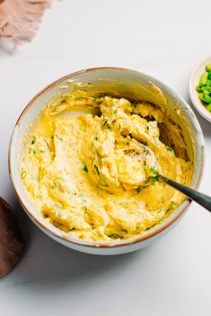 Softened butter in a bowl with garlic and green onions.