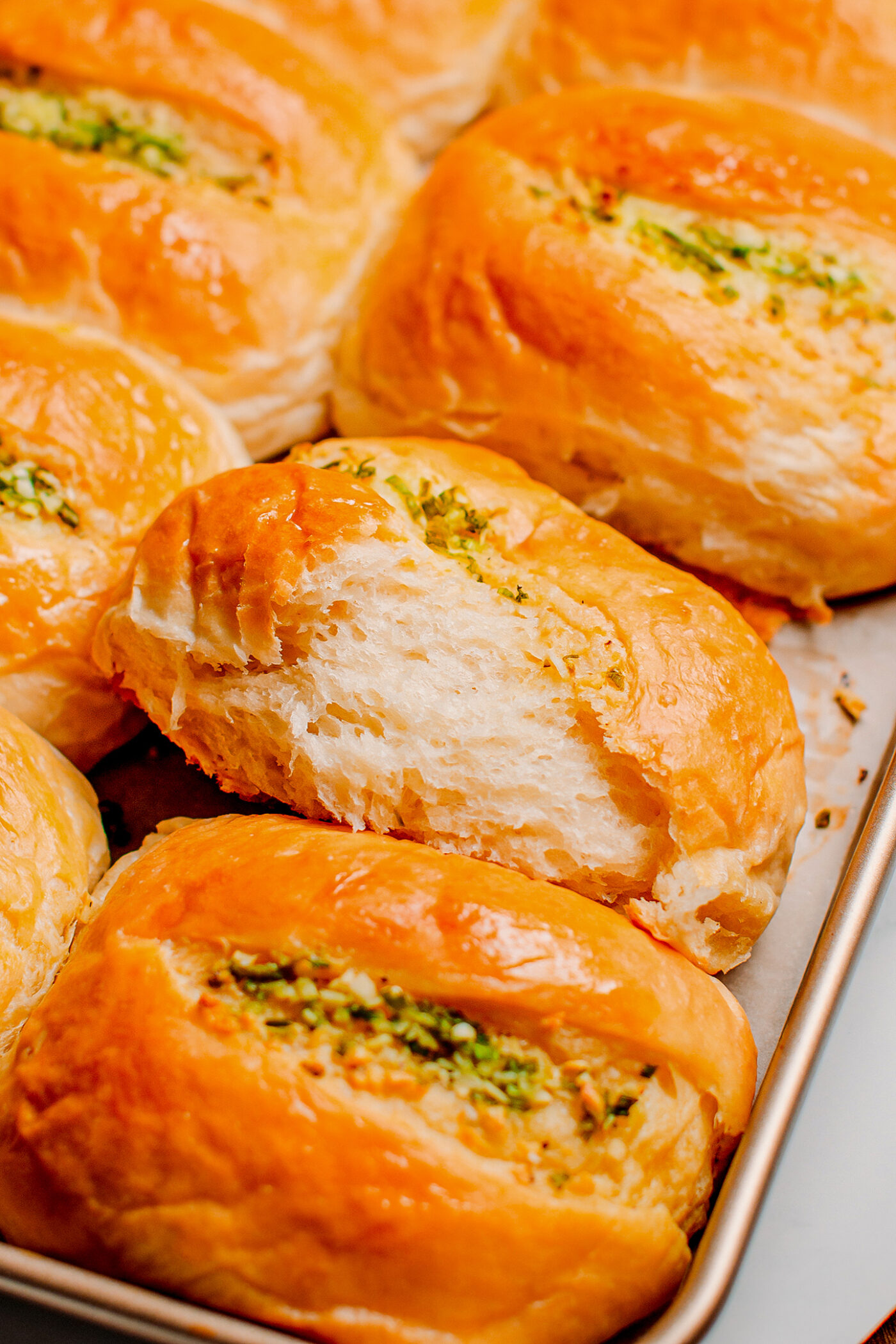 Close up of a fluffy dinner roll on a baking sheet.