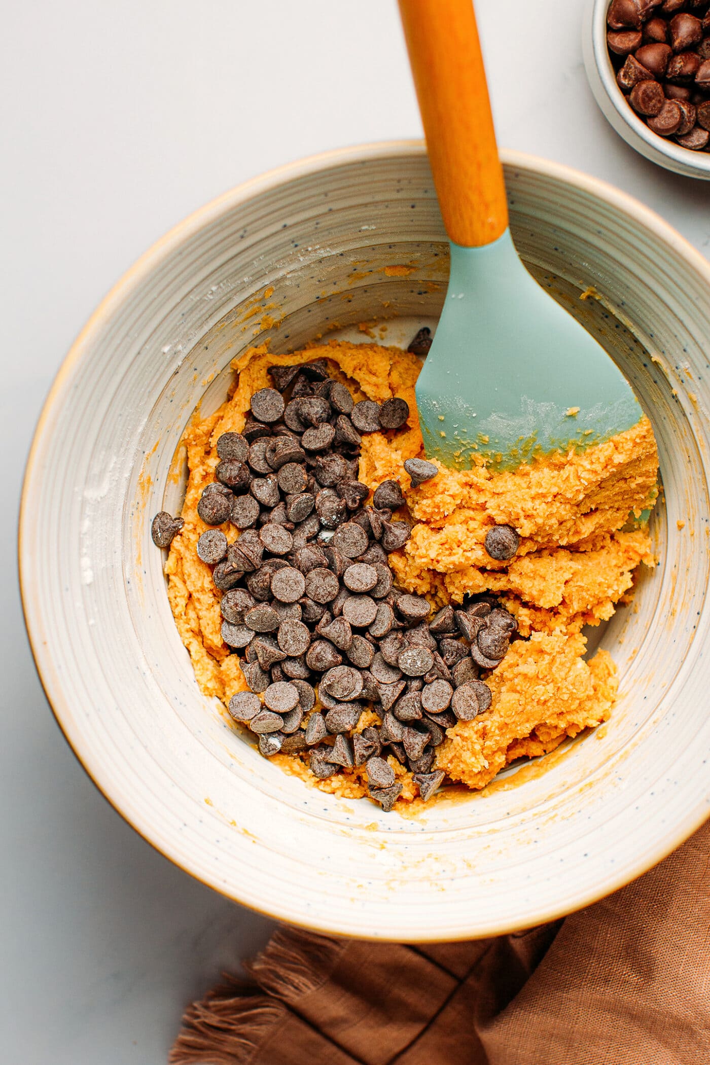 Chocolate chips and cookie dough in a mixing bowl.