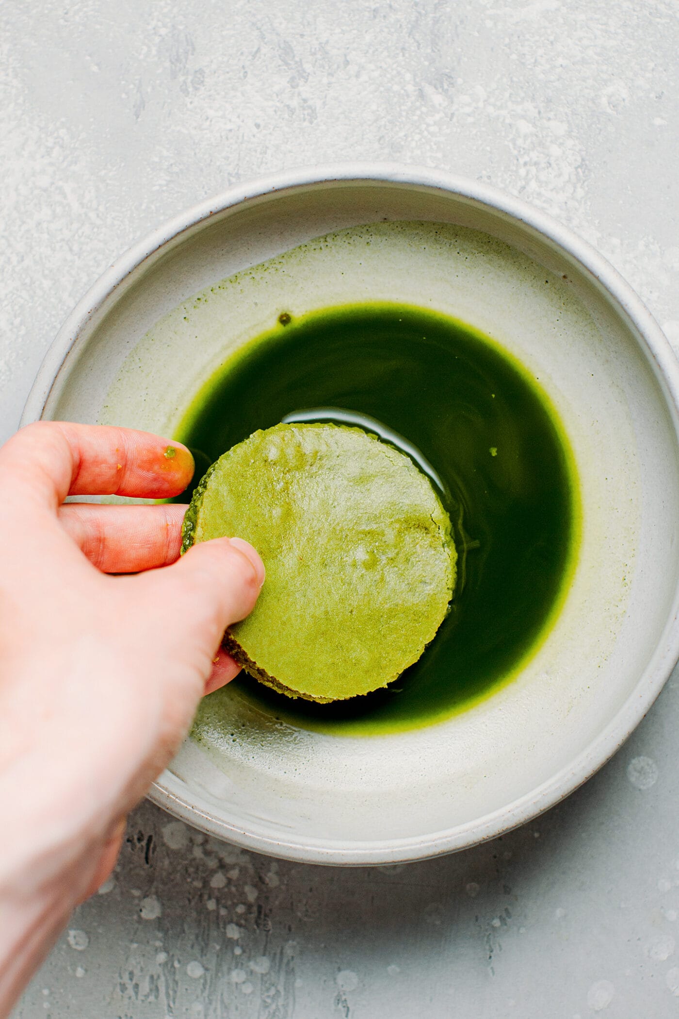 Dipping matcha sponge cake into matcha.