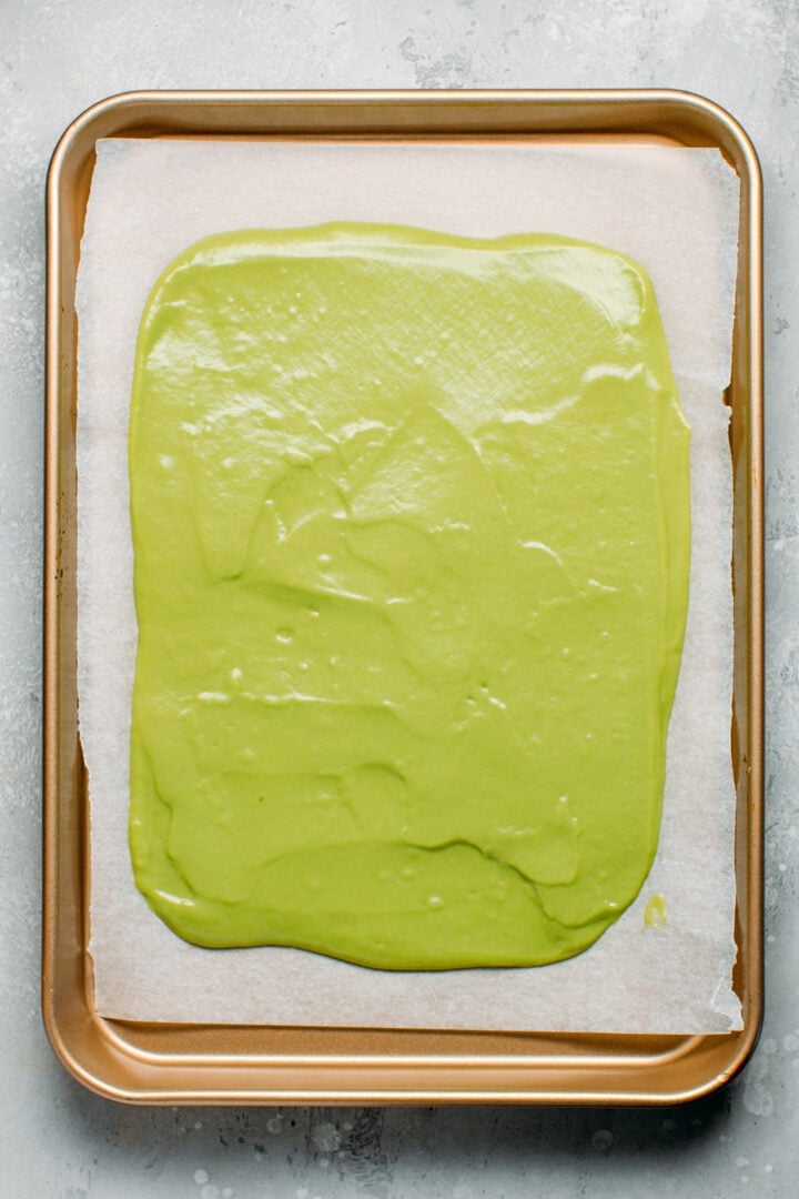 Batter of matcha sponge cake spread on a baking sheet.