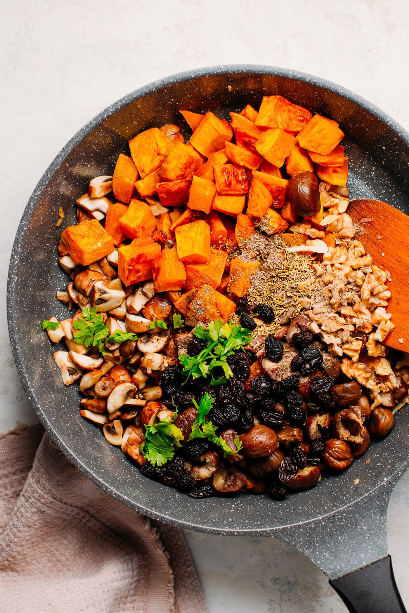 Roasted butternut squash, mushrooms, chestnuts, and herbs in a skillet.