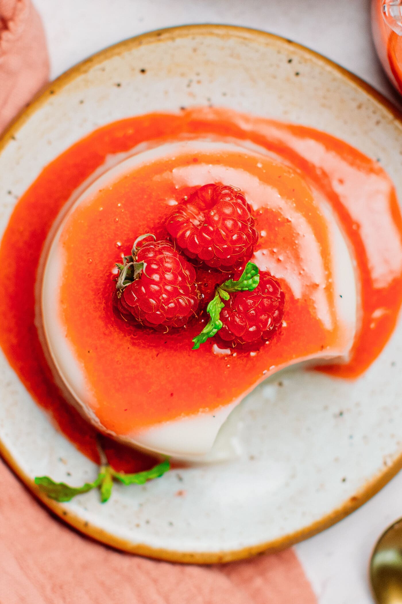 Close up of vegan panna cotta with raspberry sauce.