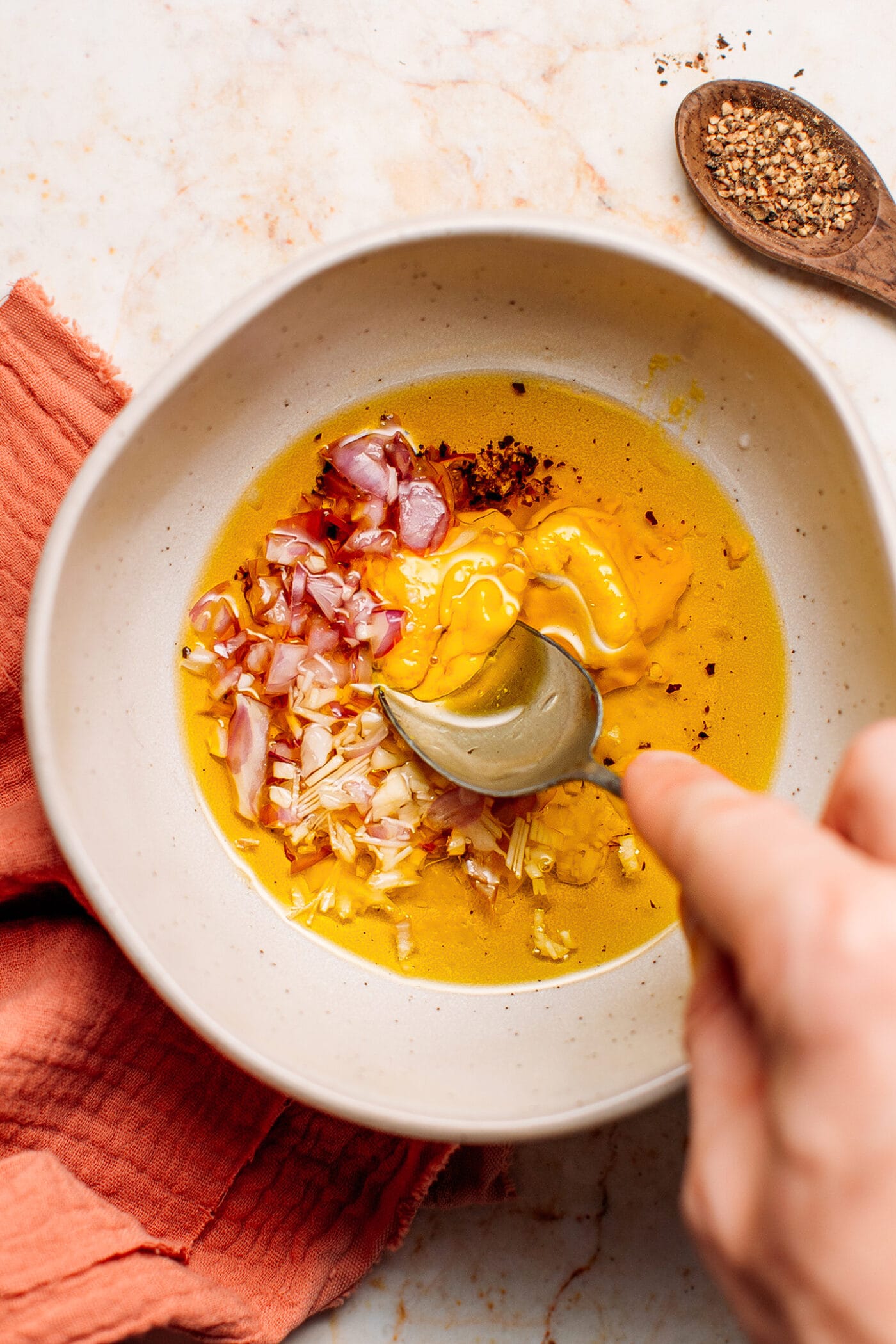 Whisking olive oil, vinegar, and mustard in a bowl.