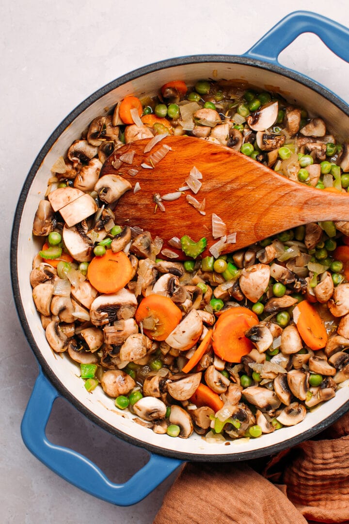 Mushrooms, carrots, and green peas in a pan.