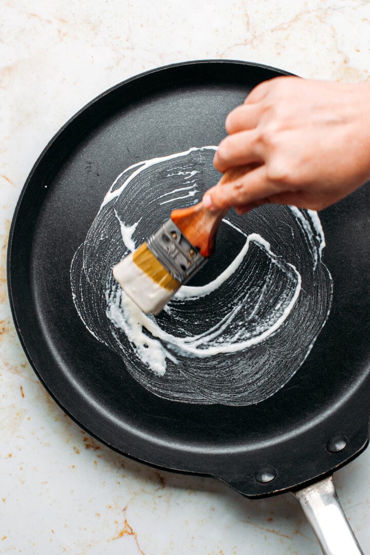 Brushing some flour batter on a non-stick pan.