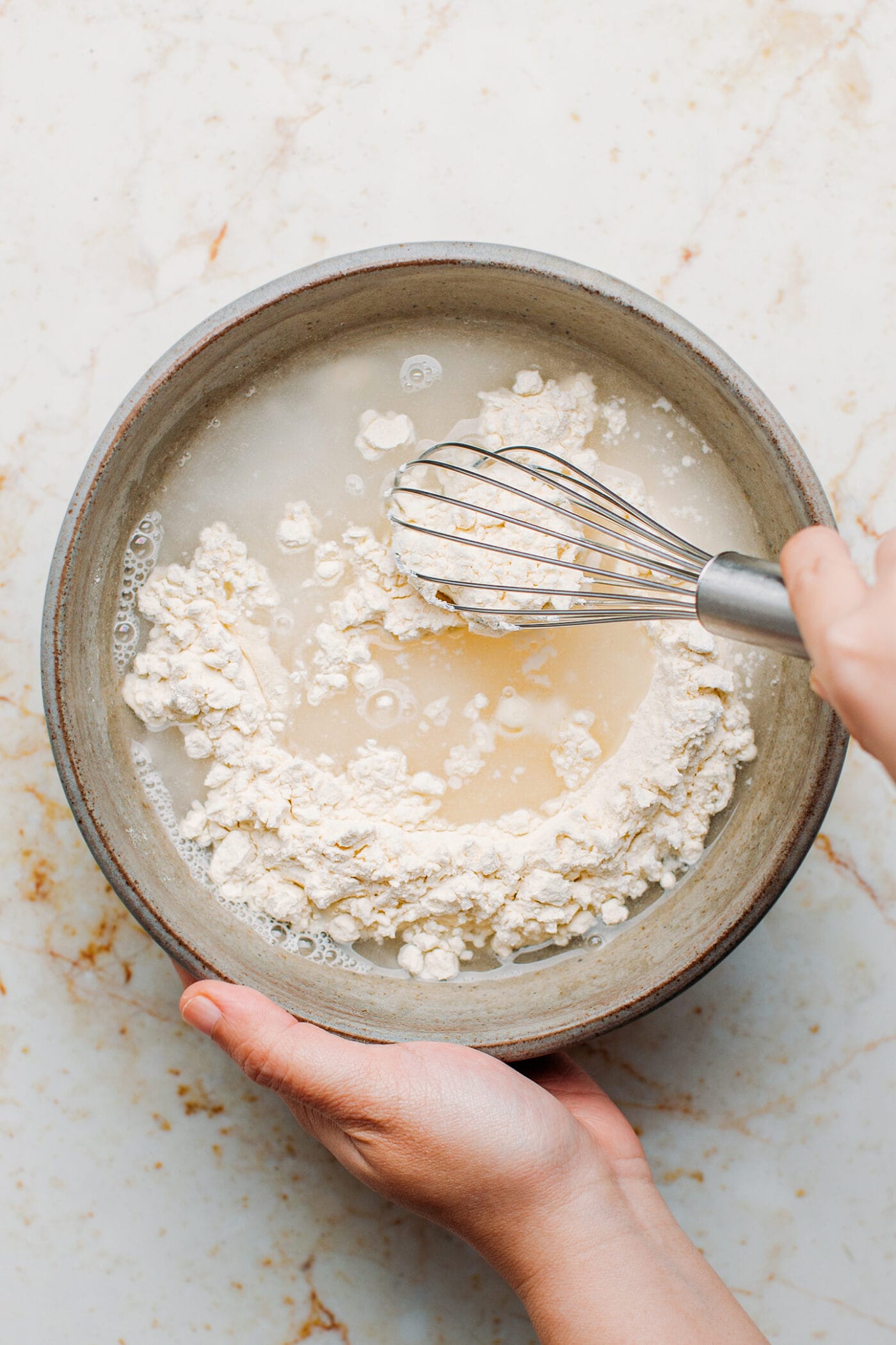 Whisking flour and water in a bowl.