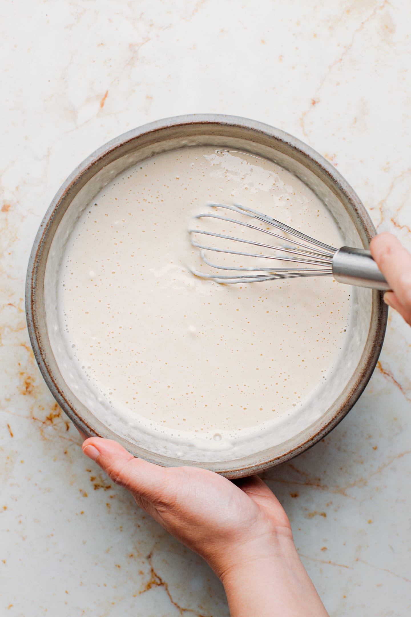 Whisking flour with water, salt, and baking powder in a mixing bowl.