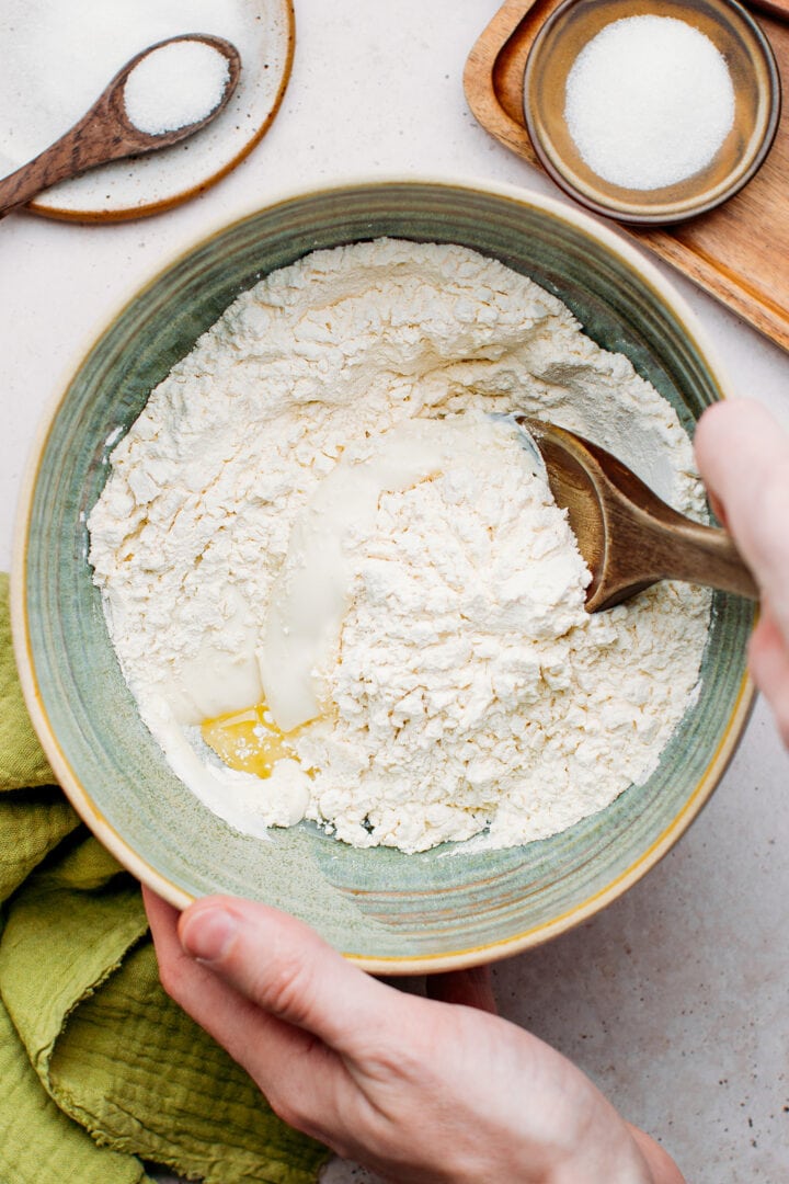 Mixing flour with yogurt and water to make naan.