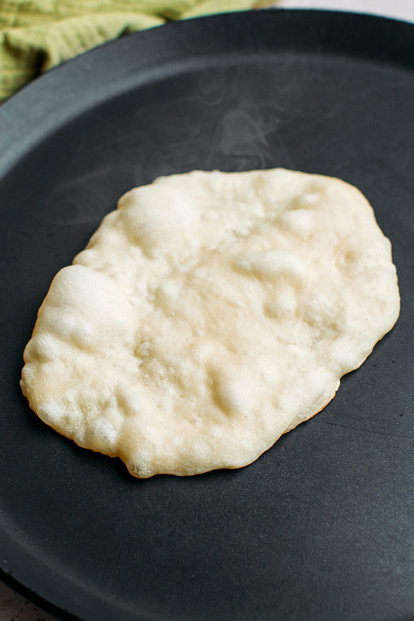 Naan bread in a skillet.