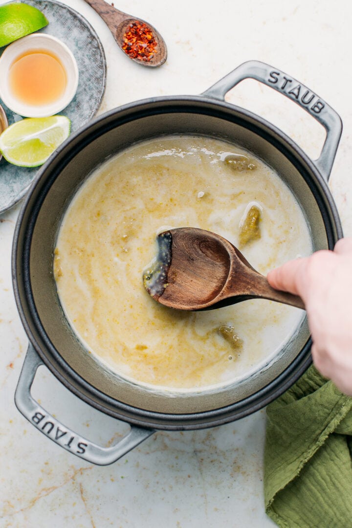 Stirring curry paste with coconut milk in a pot.