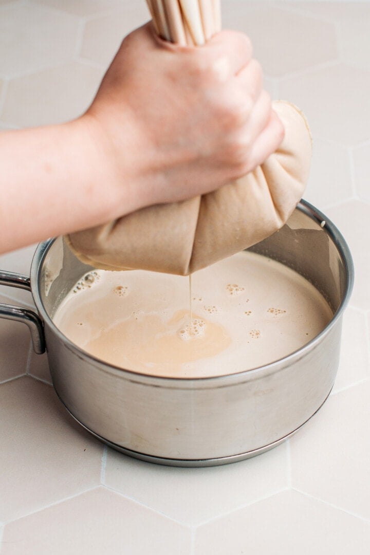 Straining peanut milk using a nut milk bag.