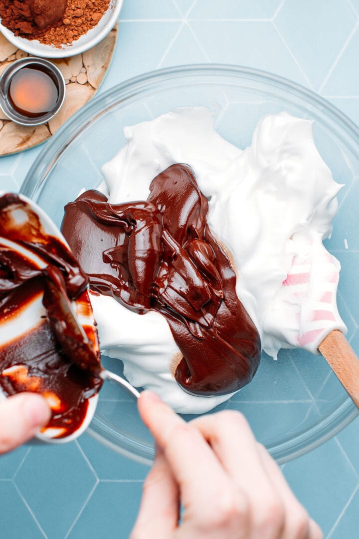 Pouring melted chocolate over whipped aquafaba.