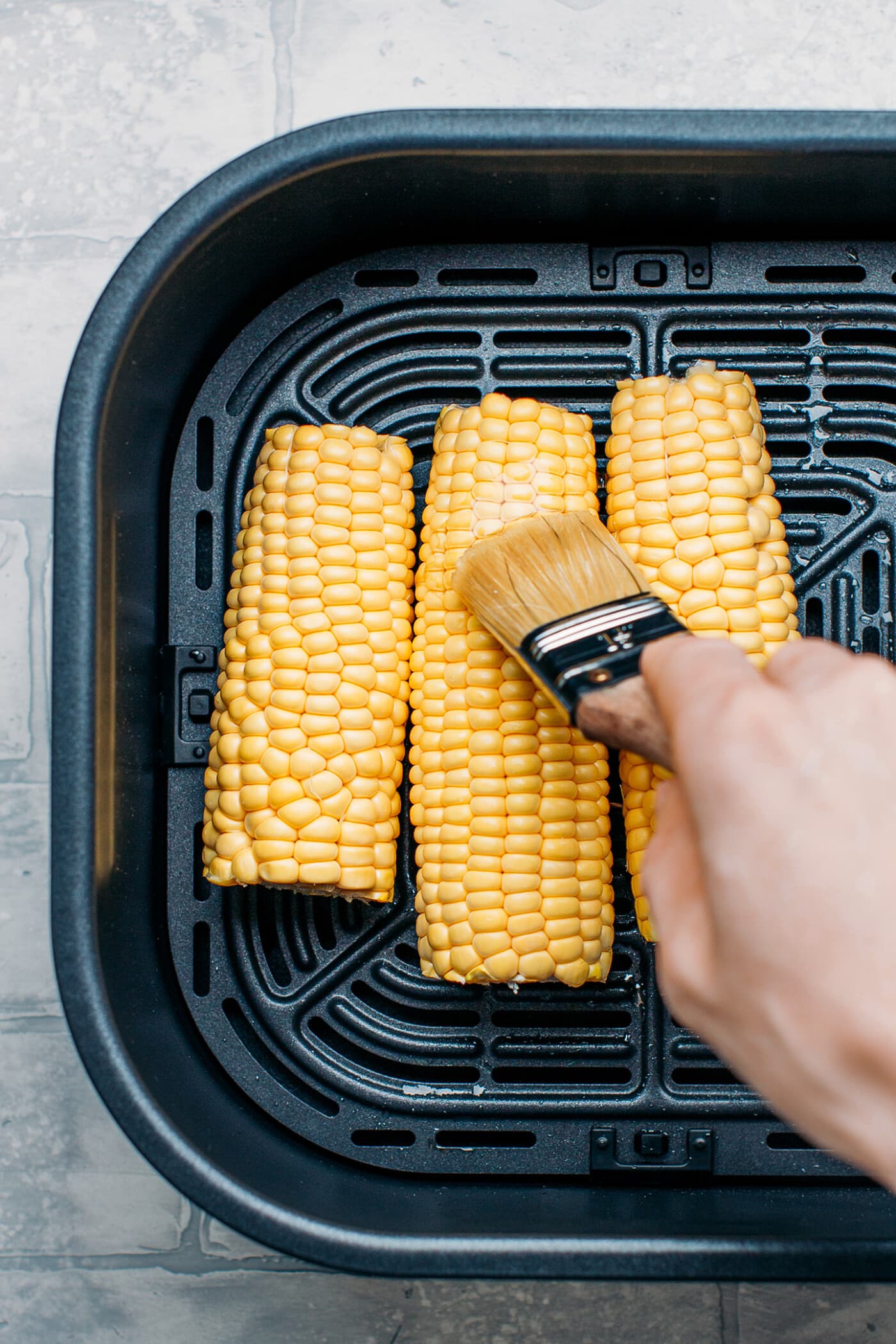 Brushing ears of corn with melted butter.