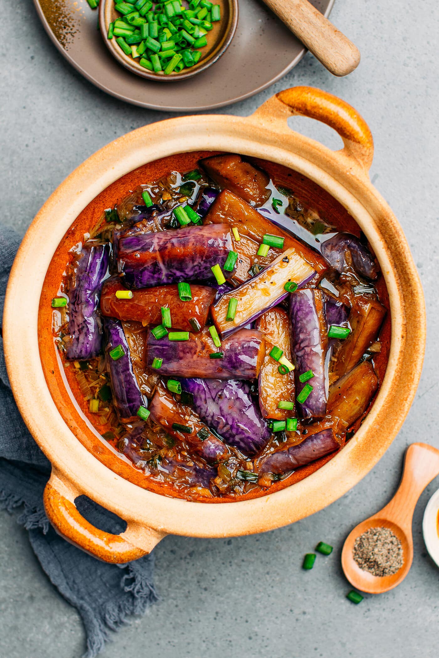 Top view of a clay pot with braised Chinese eggplants.