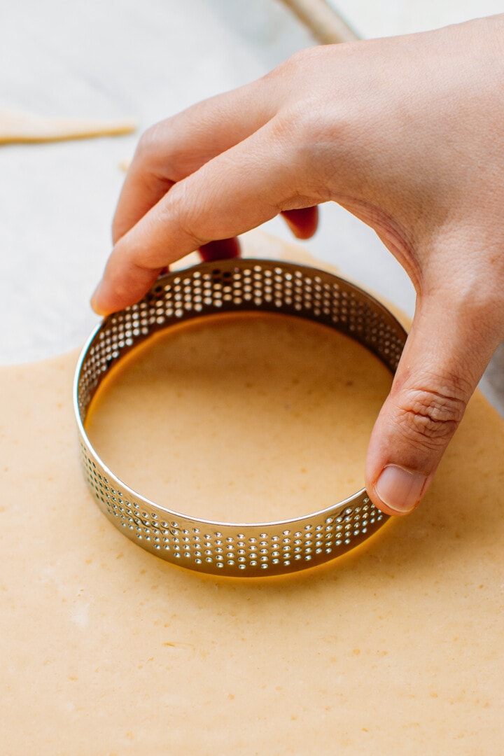 Cutting out a circle of dough using a tart ring.