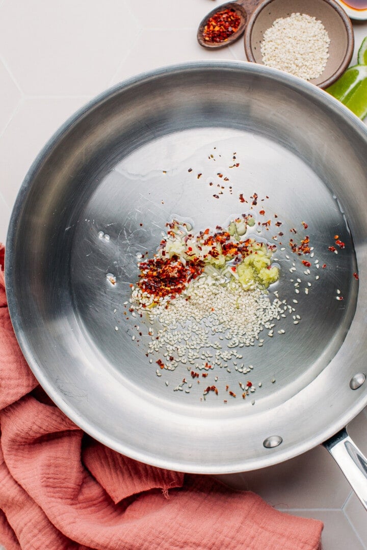 Ginger, sesame seeds, and chili flakes in a skillet.