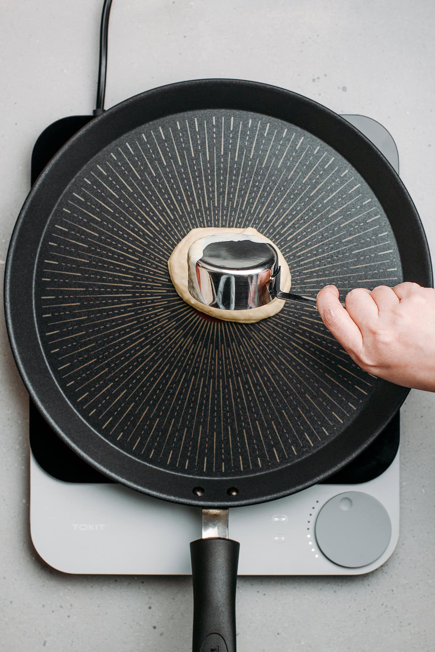 Pouring pancake batter onto a non-stick skillet.
