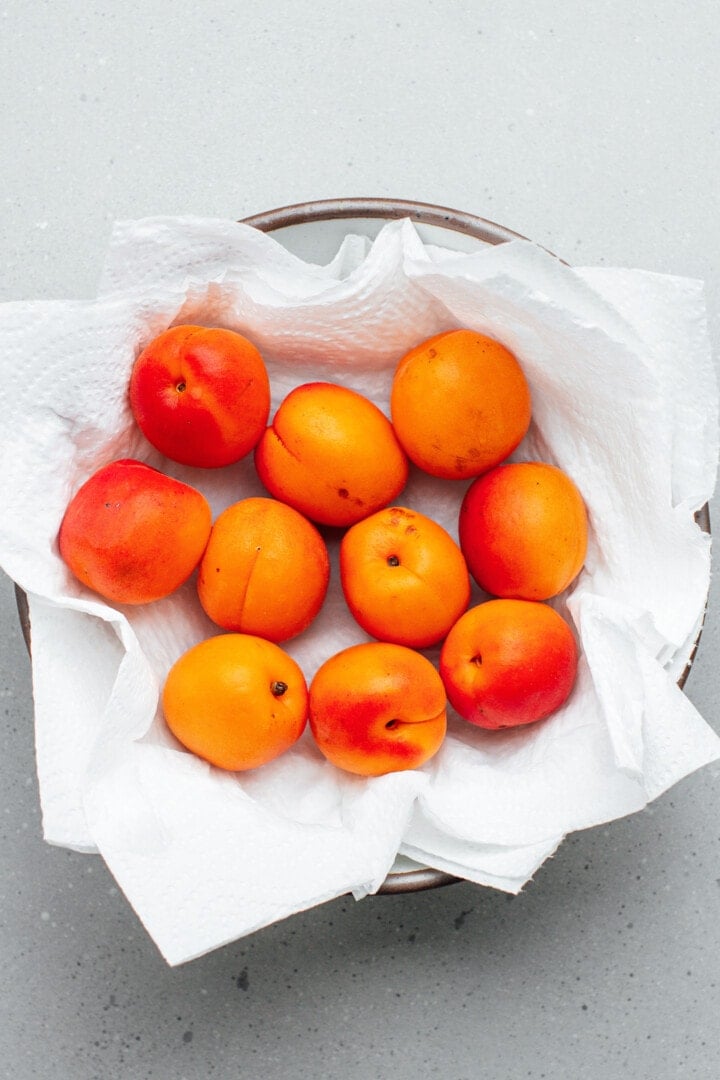 Apricots on a plate lined with kitchen paper towels.