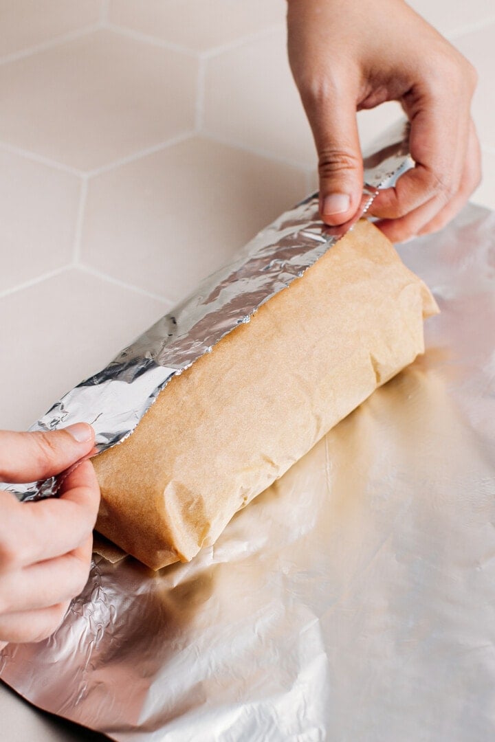 Wrapping a loaf of seitan in aluminum foil.