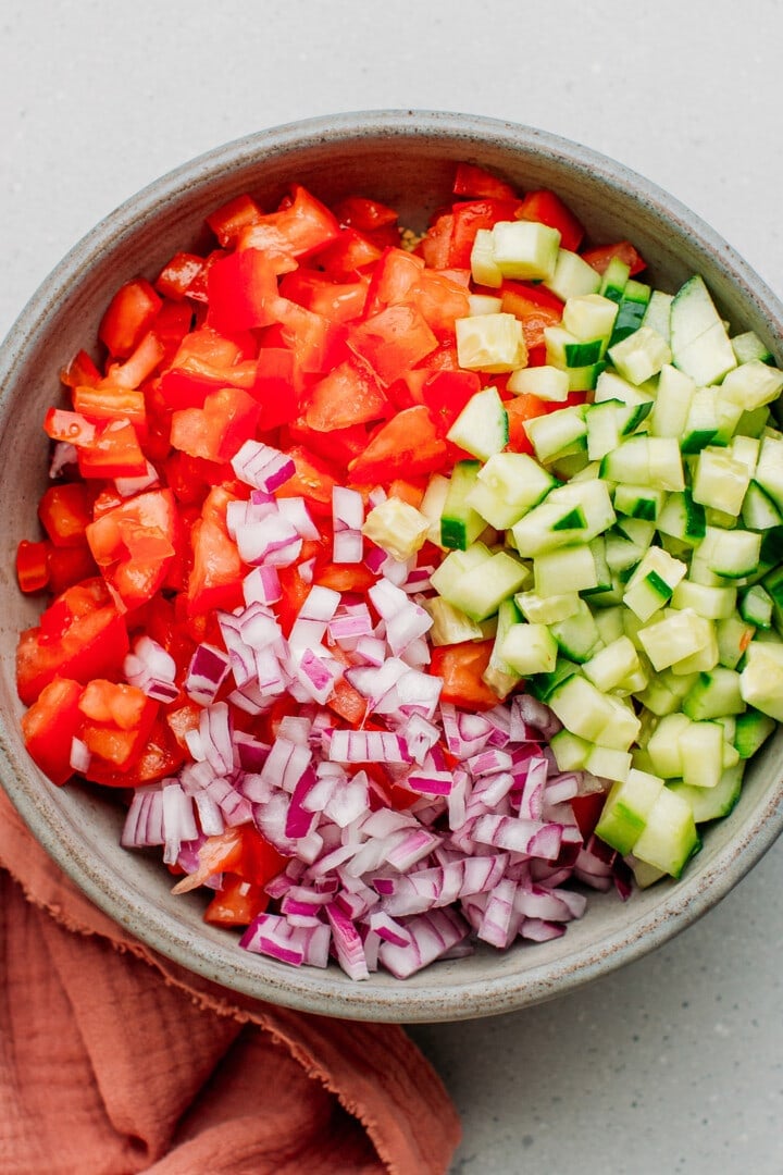 Tomatoes, cucumbers, and red onions in a bowl.