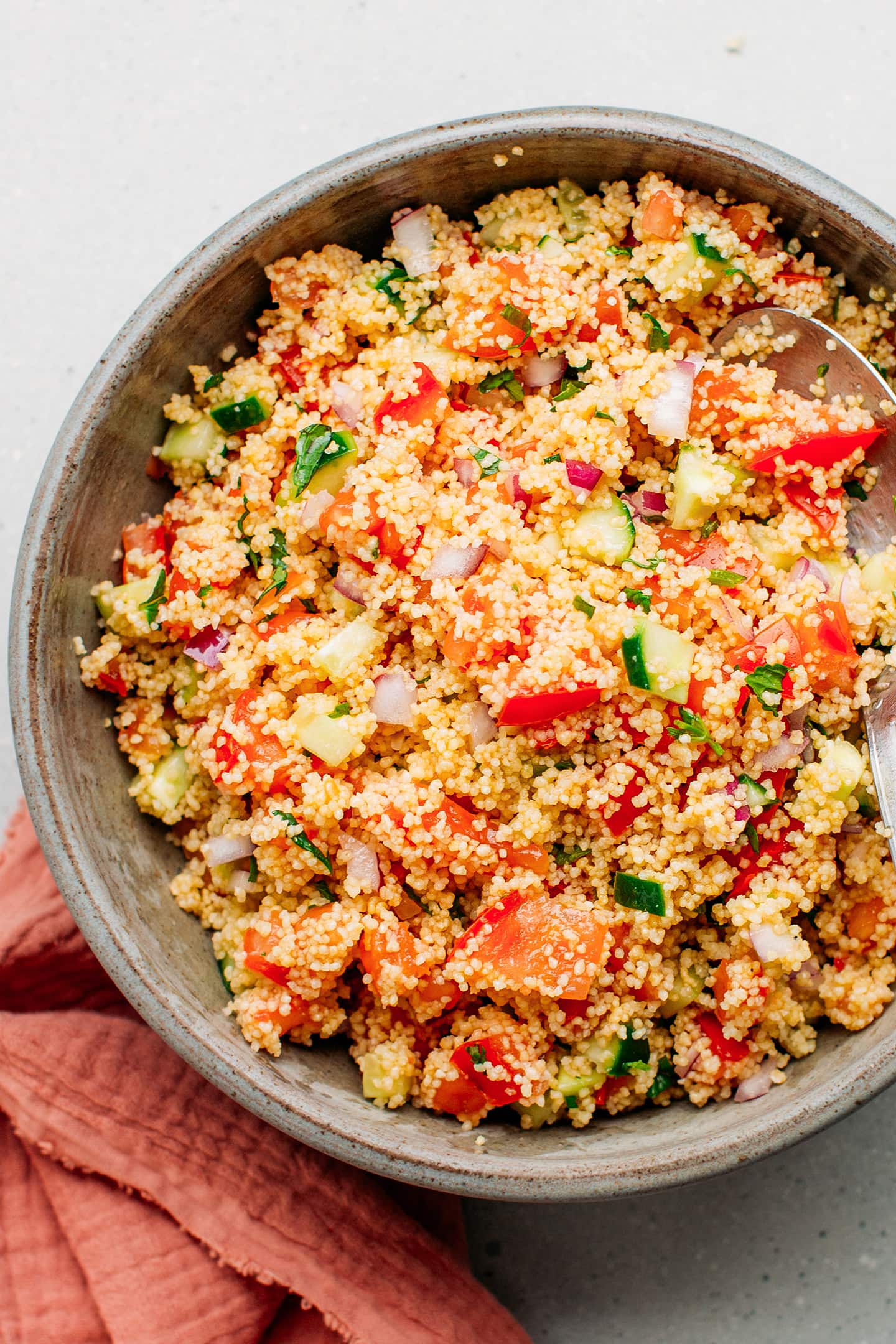 Couscous salad with cucumbers, tomatoes, and red onions in a bowl.