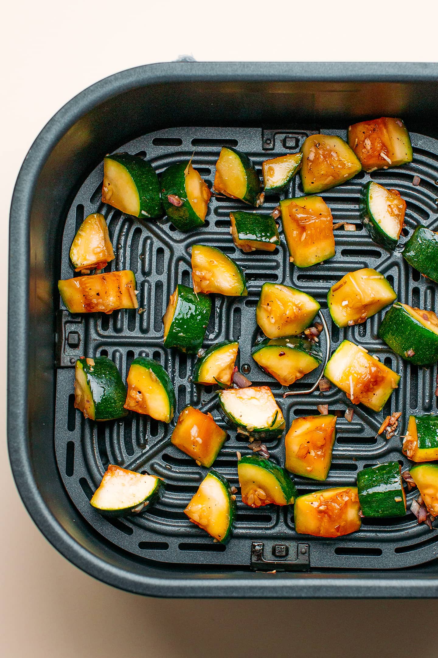 Diced zucchini in an air fryer basket.