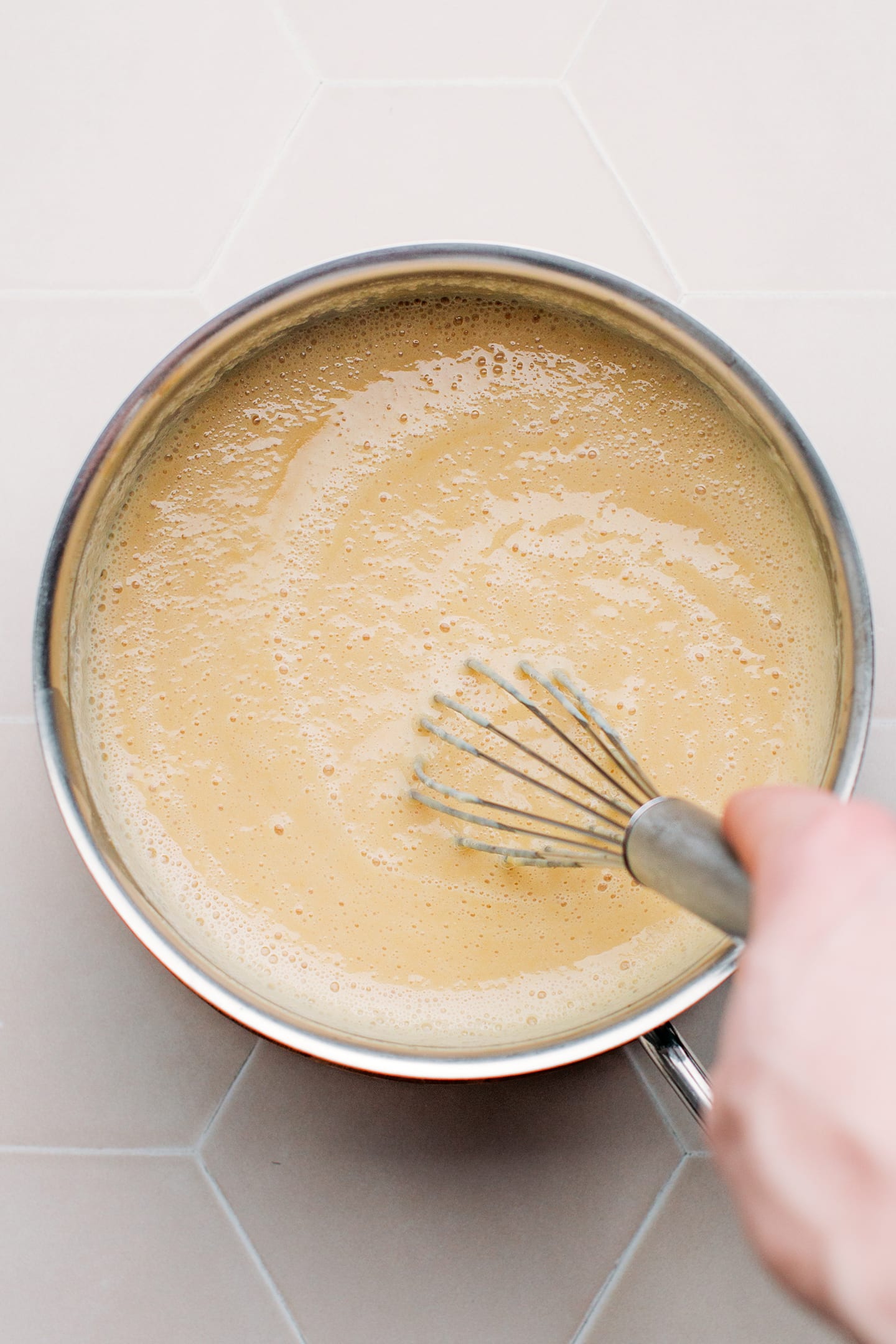 Whisking vegan cheese sauce in a saucepan.