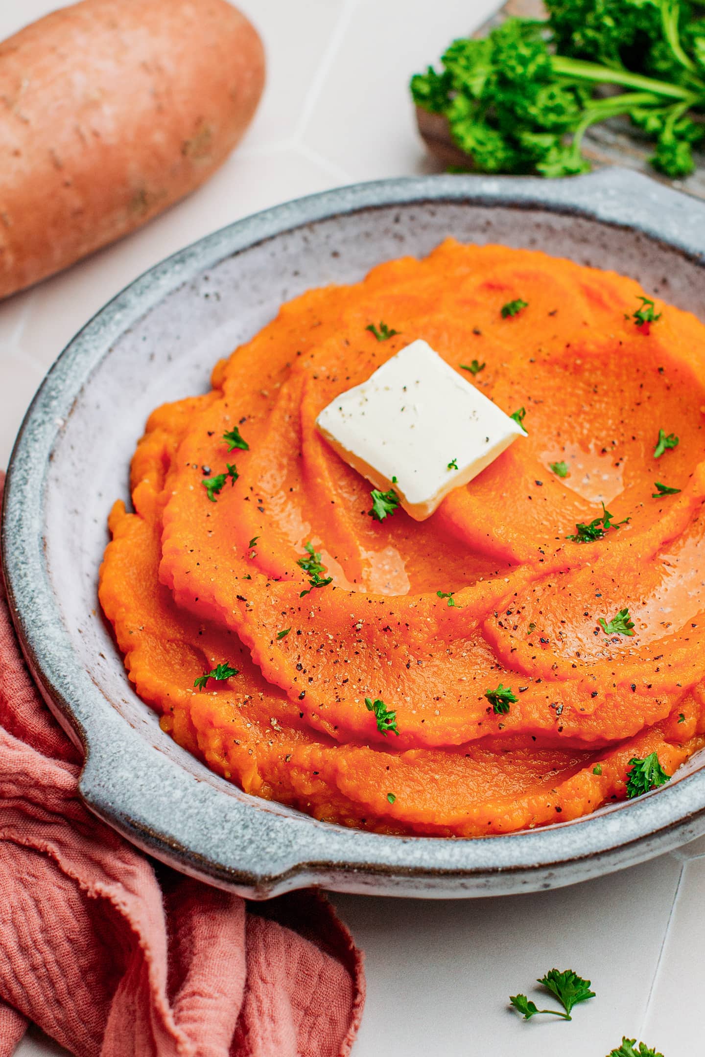 Close-up of vegan mashed sweet potatoes topped with a cube of butter.