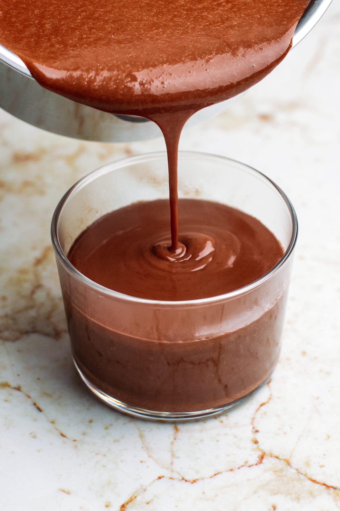 Pouring chocolate custard into a ramekin.