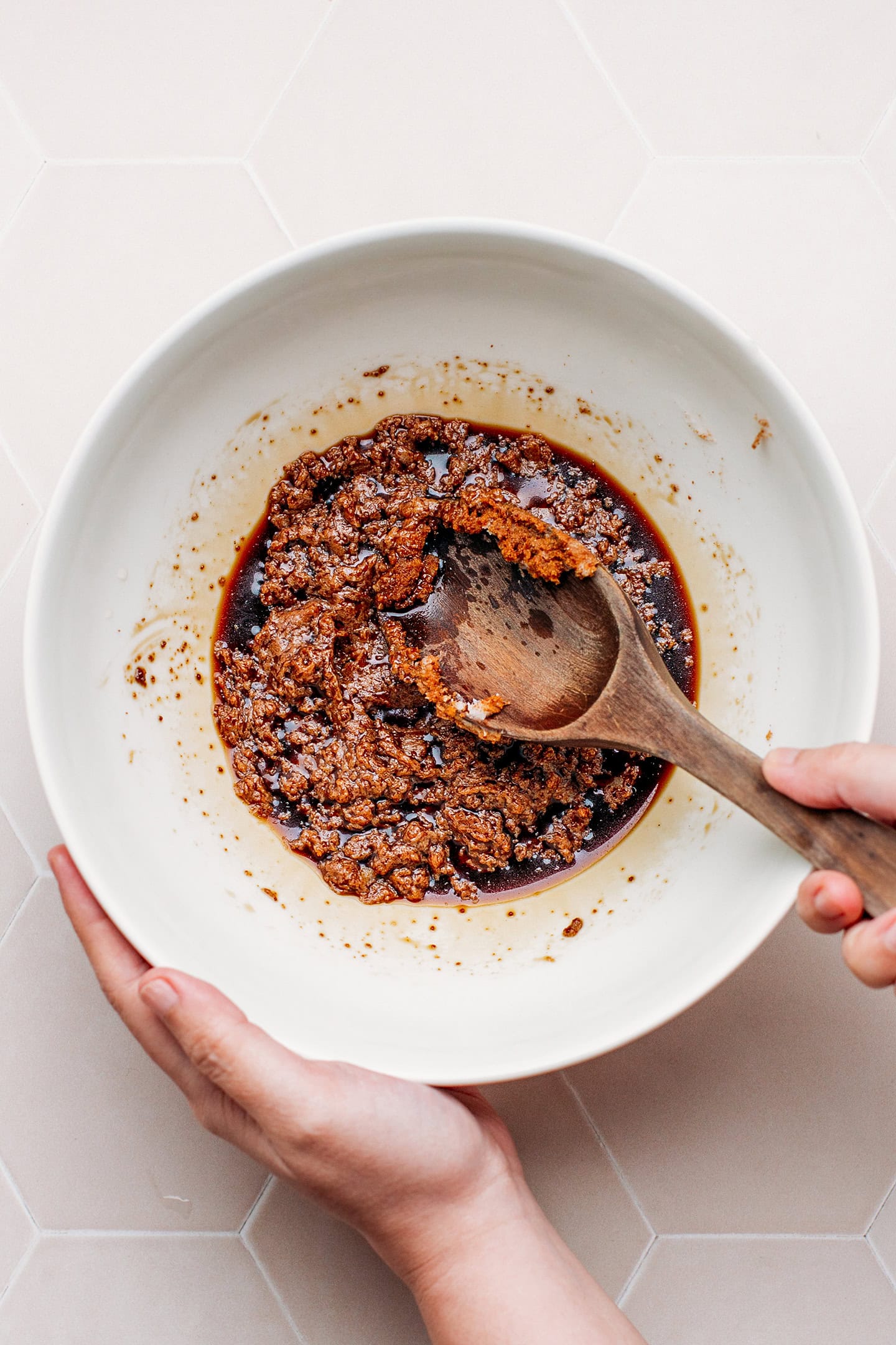 Mixing coconut sugar with oil and coconut oil in a bowl.